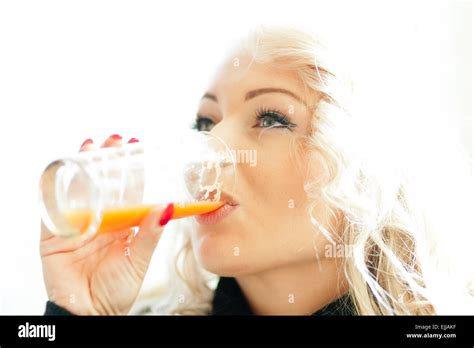 Beautiful Blonde Girl Drinking An Orange Juice With Focus On Her Beautiful Eyes Stock Photo Alamy