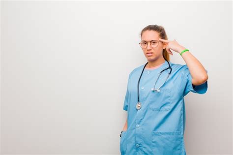 Joven enfermera latina se siente confundida y perpleja mostrando que estás loco loco o loco