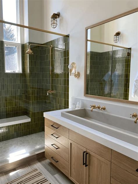 A Bathroom With Green Tile And Wooden Cabinets