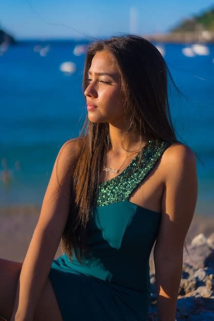 Jovem latina aproveitando o verão um vestido verde à beira mar Foto Grátis