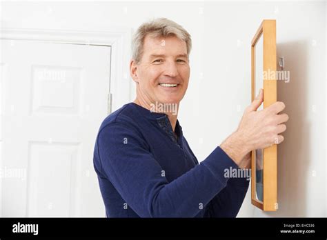 Mature Man Hanging Picture On Wall Stock Photo Alamy