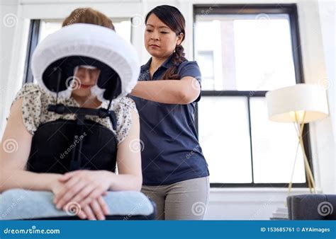 Chinese Woman Massage Therapist Giving A Neck And Back Pressure Treatment To An Attractive Blond