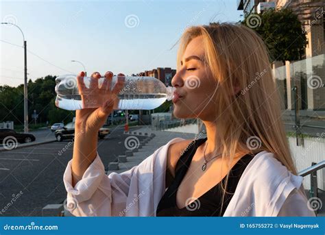 Belle Fille Blonde Avec Peau Naturelle Saine Boissons Eau De La Bouteille En Plastique Photo