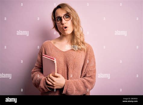 Jeune Femme Blonde Portant Des Lunettes Tenant Un Carnet Sur Fond Rose Peur En Choc Avec Un