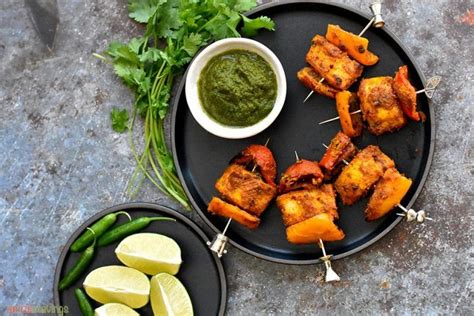 Several Skewers Of Food On A Black Plate With Limes And Cilantro