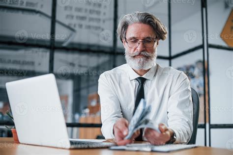homme d affaires mature aux cheveux gris et à la barbe en vêtements formels tenant de l argent