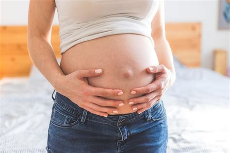 Premium Photo Happy Pregnant In Blue Jeans Mother Is Hugging Her Naked Tummy Close Up