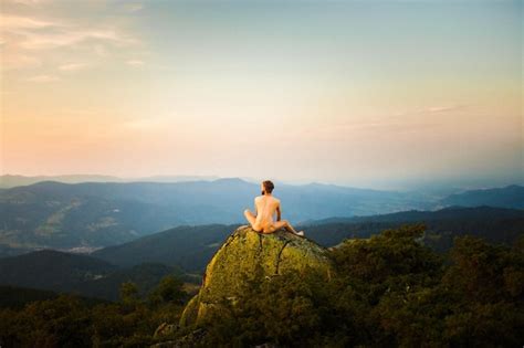Premium Photo Rear View Of Naked Man Sitting On Rock Against Mountains And Sky