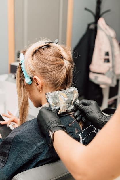 Premium Photo Dying Blonde In A Beauty Salon Hairdresser S Hands With The Client S Hair