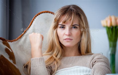 Angry Woman Sitting On Armchair At Home Looking At Camera Negative