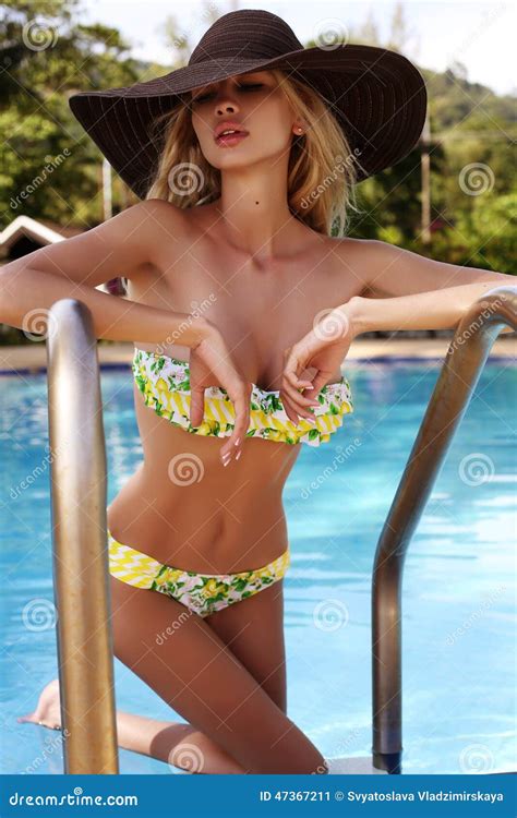 Mujer Atractiva Con El Pelo Rubio En El Bikini Y El Sombrero Que Se Relajan En Piscina Imagen De