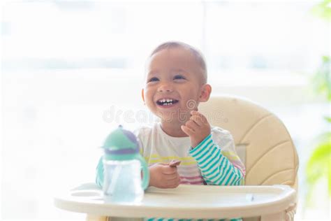 Baby Eating Solid Foods In High Chair Stock Photo Image Of Parent