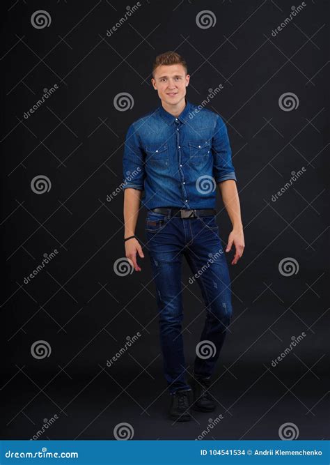 A Guy Poses by Bending One Leg Against a Black Background Stock Photo