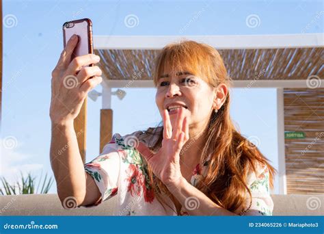 Mujer Latina Sentada En Una Terraza Hablando En Una Videollamada Con Un Amigo Foto De Archivo