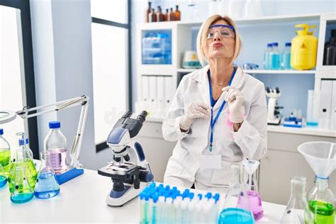 Middle Age Blonde Woman Working At Scientist Laboratory Looking At The Camera Blowing A Kiss On