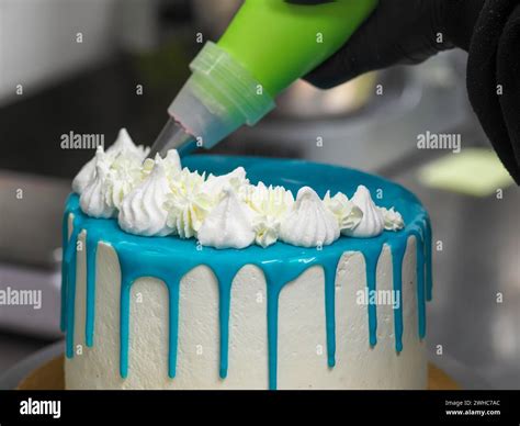 Decorating A Cake With White Icing Using A Pastry Bag With Blue