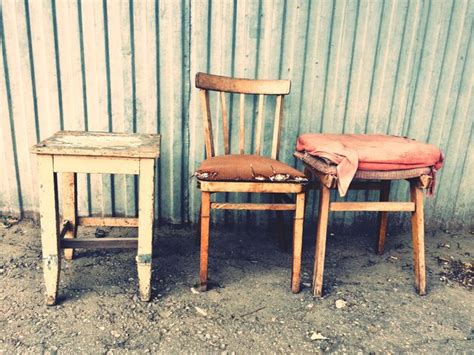 Premium Photo Abandoned Chair And Tables Against Corrugated Iron