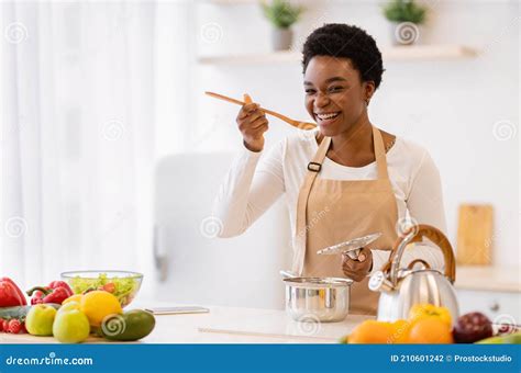 Happy African American Woman Cooking Tasting Dinner In Kitchen Indoor