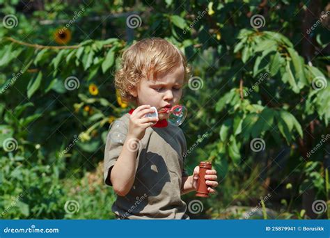 Het Jonge Blonde Jongen Blazen Bellen Op Een Zonnige Dag Stock Afbeelding Image Of Europees