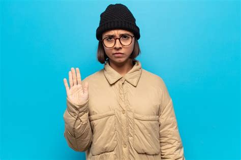 Jovem latina parecendo séria severa descontente e irritada mostrando a palma da mão aberta