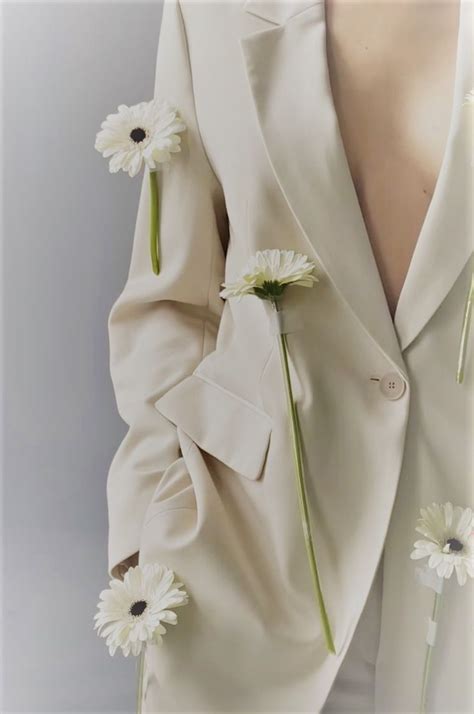 A Man In A White Suit With Daisies On His Lapel And Back Pocket