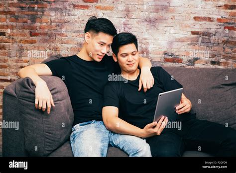 Asian Gay Couple Watching And Looking At Phone Tablet Together Portrait Of Happy Gay Men