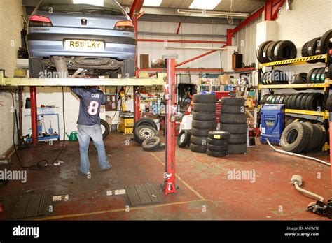 Car Up On Hydraulic Lift At A Garage Mechanic Working Underneath Stock