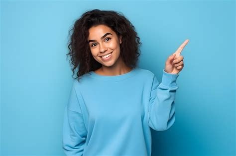 Mujer joven señalando con el dedo a la chica latina de lado aislada en azul Foto Premium