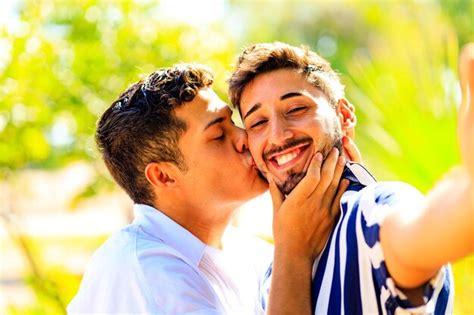 Casal gay feliz tirando uma selfie câmera de celular inteligente no parque de verão Foto