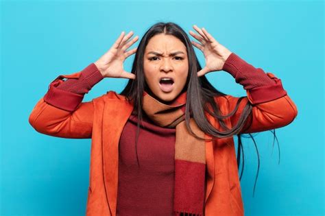 Mujer latina gritando con las manos en alto sintiéndose furiosa frustrada estresada y molesta