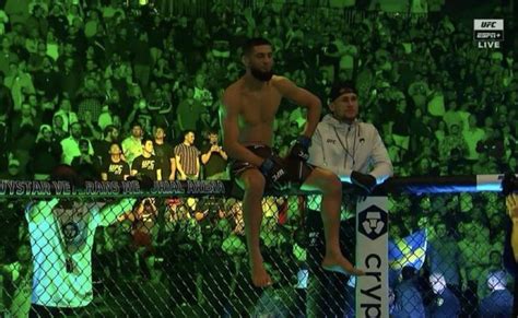 A Man Standing On Top Of A Fence Next To Another Man In Front Of A Crowd