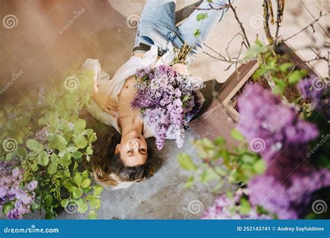 A Topless Blonde In A White Shirt And Jeans On The Floor With Lilac Flowers Stock Image Image
