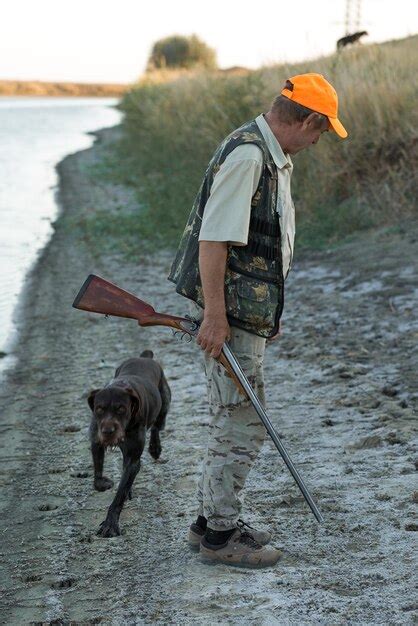 Duck Hunter With Shotgun Walking Through A Meadow Xarear View Of A Man