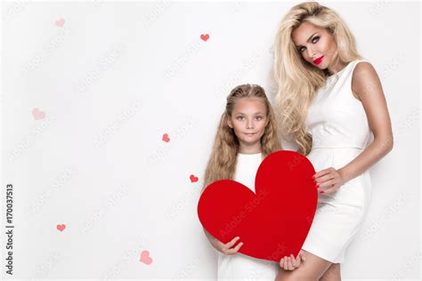 Beautiful Blonde Woman Mother And Daughter Standing On A White Background And Holding A Red