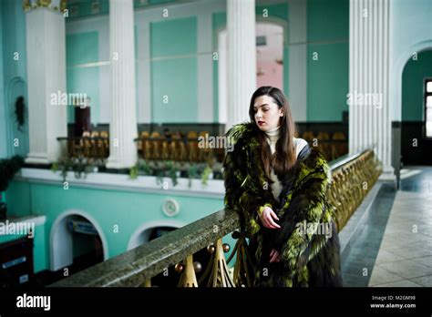 Brunette Girl In Green Fur Coat In Old Hall With Column And Railings