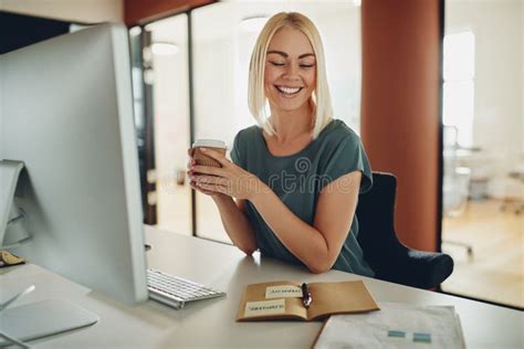 Smiling Young Businesswoman Drinking Coffee While Working At Her Stock