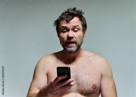 Portrait Of A Wild Unkempt Unshaven Middle Aged Naked Man Of 40 Years With A Phone In A Burgundy