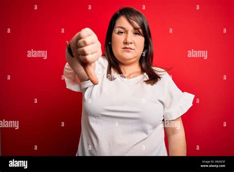 Beautiful Brunette Plus Size Woman Wearing Casual T Shirt Over Isolated Red Background Looking