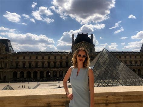Une belle blonde européenne se tient souriante devant le musée du Louvre à Paris la capitale
