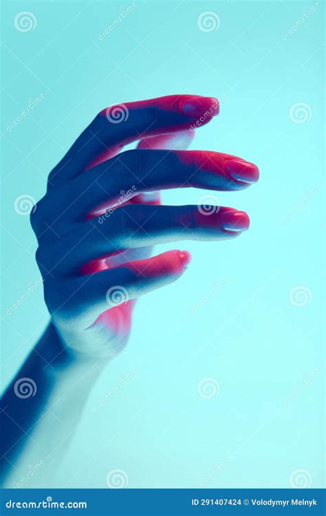 Elegant Female Hand Isolated Over Blue Background In Neon Light Natural Nude Nails Manicure