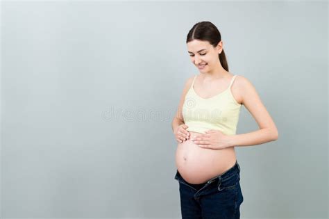 Naked Pregnant Woman Belly Wearing Opened Jeans At Colorful Background With Copy Space