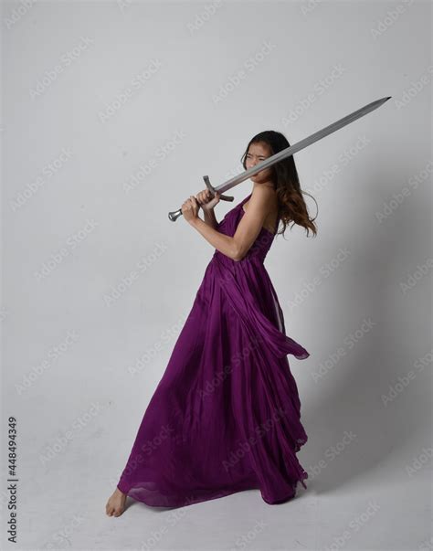 Full Length Portrait Of Pretty Brunette Asian Girl Wearing Purple Flowing Gown Sitting Pose