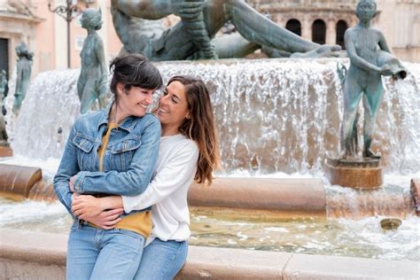 Una joven pareja de lesbianas hispanas sentada en una fuente en valencia concepto gay y lésbico