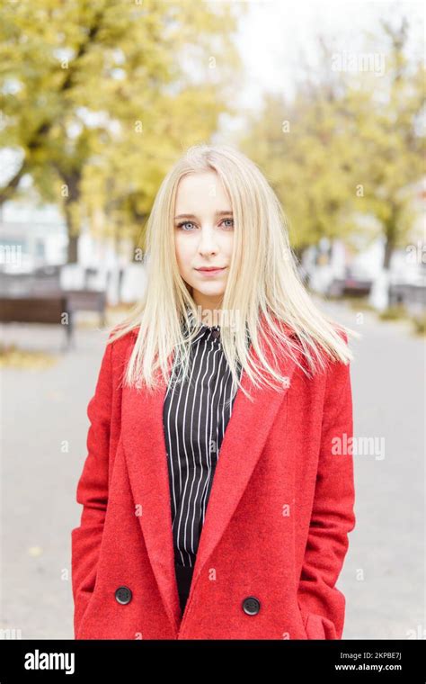 Une jeune femme blonde se promène dans la ville d automne sous un manteau rouge Le concept de