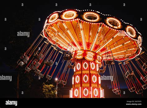 Illuminated Swing Chain Carousel In Amusement Park At Night Stock Photo