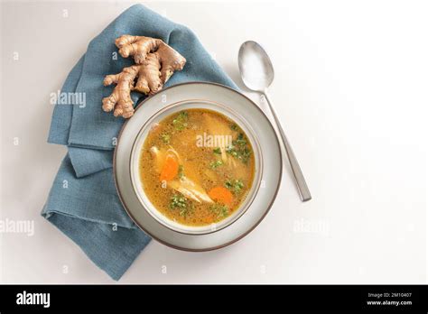 Healthy Soup From Chicken Meat Vegetables And Ginger In A Bowl On A Blue Napkin And A Gay White