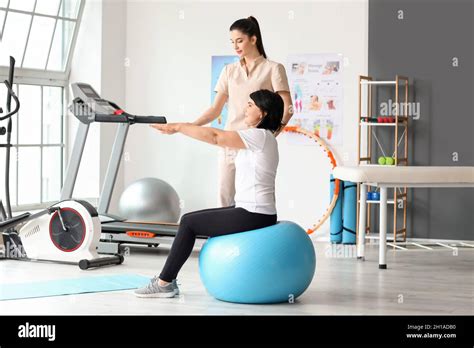 Mature Woman Training With Fitball And Physiotherapist In