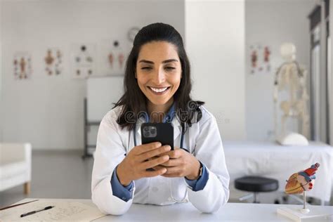 Feliz Joven Doctora Latina Escribiendo Un Mensaje En Un Smartphone Foto De Archivo Imagen De