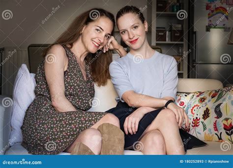 Portrait Of A Mature Mother And Her Teenage Daughter Looking Camera Sitting At Home Stock Image