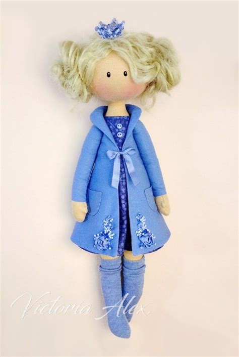 A Doll With Blonde Hair Wearing A Blue Dress And Boots Is Hanging On